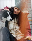woman in chalk white-dune beige checkered shirt and grey beanie petting a dog