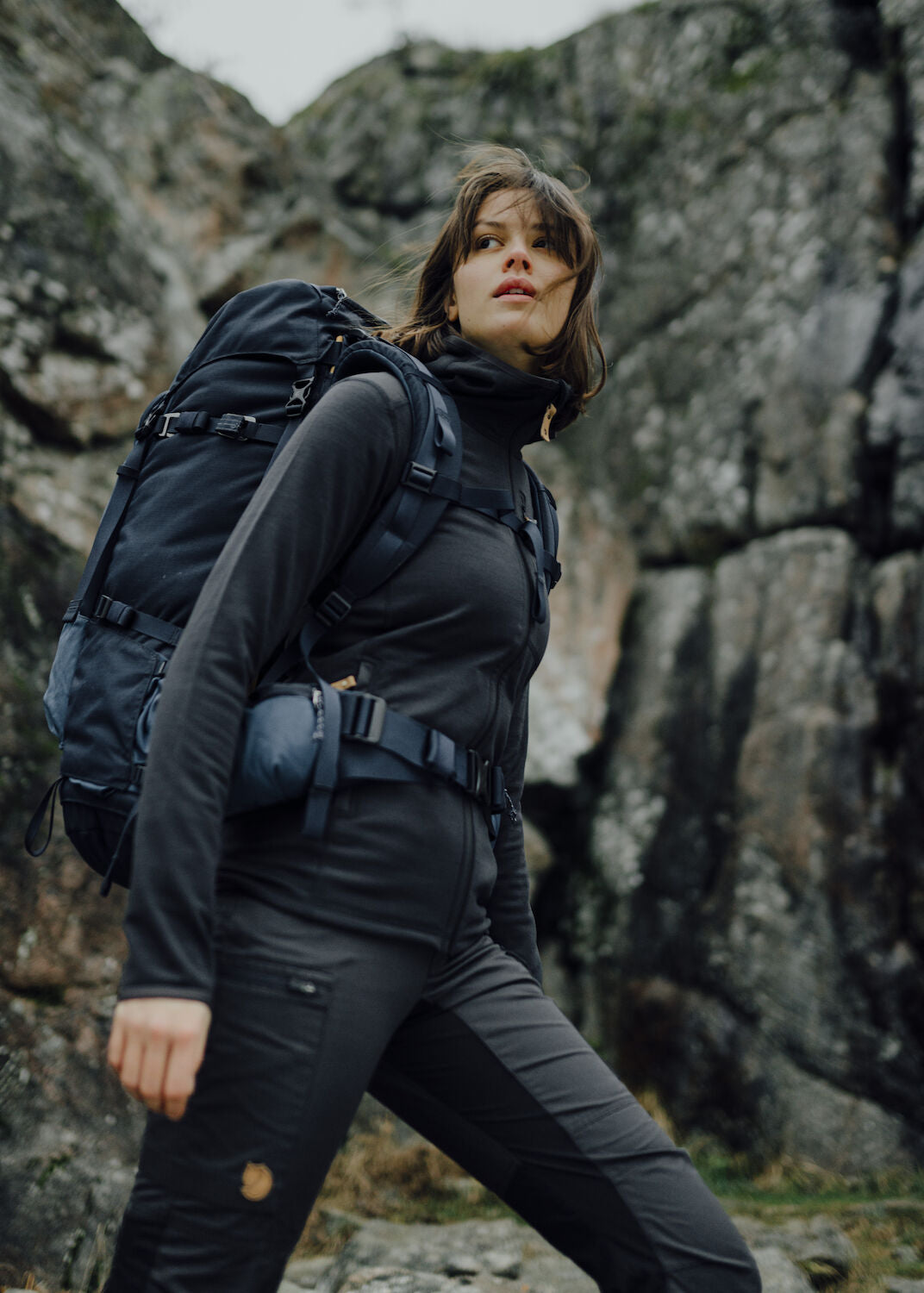 woman in a black top and black bottom carrying a trekking backpack