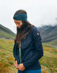Person wearing a blue jacket with a mountainous landscape in the background